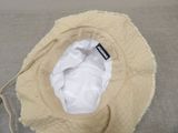 a hat with a tag on it sitting on a bed
