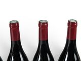 three bottles of red wine are lined up on a white surface