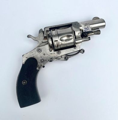 un revolver argenté avec une poignée noire sur une surface blanche