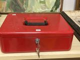 a red metal box sitting on a table with a key in it