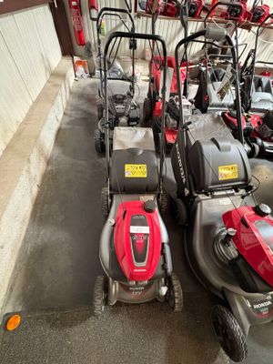 Plusieurs tondeuses à gazon sont alignées en rang dans un garage
