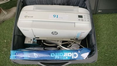 une imprimante posée dans une valise, sur l'herbe