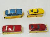 four toy cars are lined up in a row on a white surface