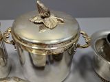 a silver plate with a bird on it next to other silver dishes