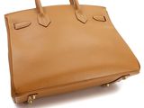 a tan leather handbag on a white background