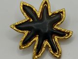 a close up of a black and gold pin with a star on it