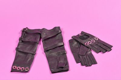 des gants en cuir noir et une paire de gants sur fond rose