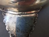 a silver vase with a bird on it on a table