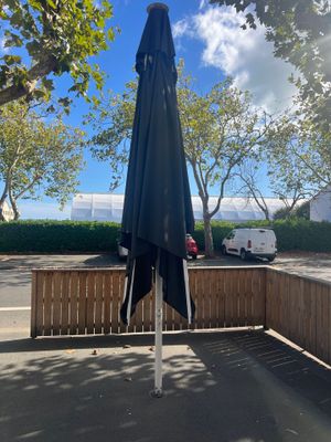 a black umbrella sitting on a wooden bench next to a parking lot