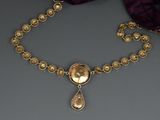 a close up of a gold necklace with a purple scarf behind it