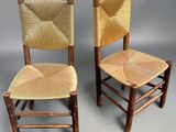 pair of wooden chairs with woven seats against a gray background