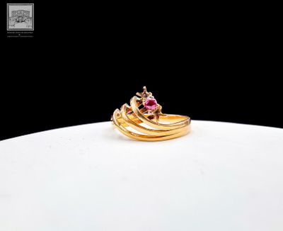 une bague en or sertie d'une pierre rose, posée sur une assiette blanche