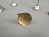 several silver candlesticks and a gold candle holder on a table