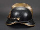 an old black helmet with gold trims and a leather strap