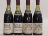 four bottles of wine are lined up on a white surface