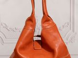 a brown leather bag sitting on top of a wooden table