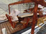 a wooden table and chairs on the deck of a boat