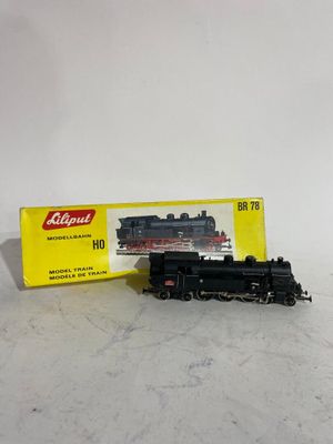 une locomotive noire et rouge posée à côté d'une boîte jaune