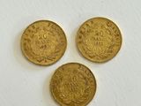 three gold coins on a white surface