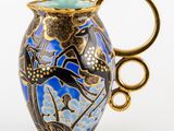 a blue vase with a gold handle on a white background