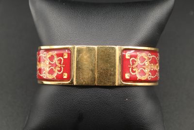 un gros plan d'un bracelet rouge et doré sur un mannequin