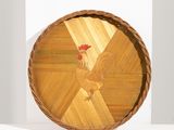une assiette en bois sur laquelle est représenté un coq, posée sur une étagère