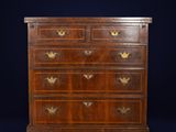 a walnut chest of drawers with brass handles