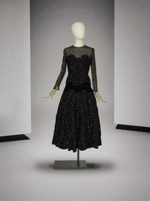 une robe noire posée sur un mannequin dans une pièce blanche