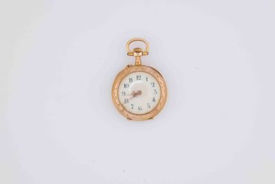 a close up of a gold pocket watch on a white surface