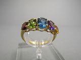 une image d'une bague ornée de pierres multicolores posée sur un socle transparent