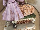 a figurine of a woman in a purple dress sitting on a bench