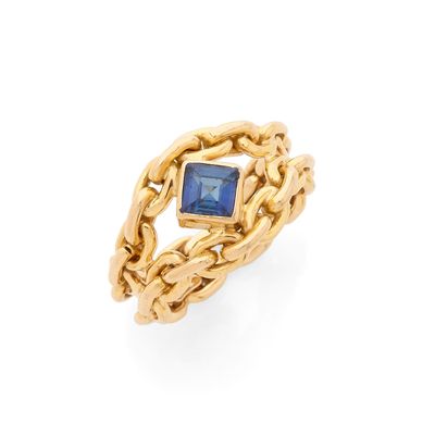 une bague en or sertie d'une pierre bleue et entourée d'une chaîne