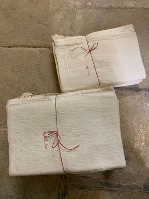 deux serviettes blanches, attachées par un cordon rouge, posées sur un sol carrelé