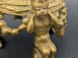 a gold vase on a table with a bird on top of it
