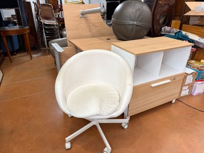 a white chair sitting in front of a desk with a ball on it