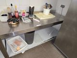 a stainless steel counter top with a trash can and other items