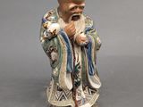 figurine chinoise représentant un vieil homme barbu tenant un oiseau