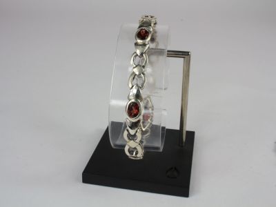 silver bracelet with garnets on display on a black stand