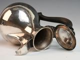a silver tea pot with a pair of goggles on it