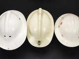 three white hard hats sitting on top of a black table