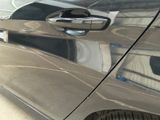 a close up of a car door handle with a reflection of a building in the background
