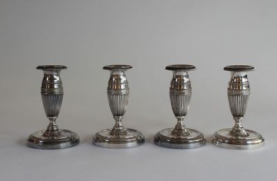 three silver candlesticks are lined up on a white surface
