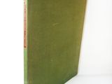 an old book with a green cover sitting on top of a white table