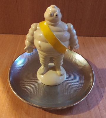 une petite statue représentant un homme corpulent, posée sur un plateau en argent