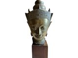 bronze head of a buddha statue on a wooden base
