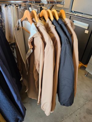 des vêtements suspendus à un portant dans un magasin de vêtements, à côté d'un réfrigérateur