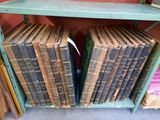 Des livres sont empilés sur une étagère dans une pièce dont l'un des murs est rouge.