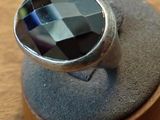 a silver ring with a faceted black stone on it
