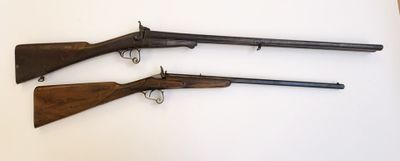 trois vieilles armes à feu posées sur une table, sur fond blanc