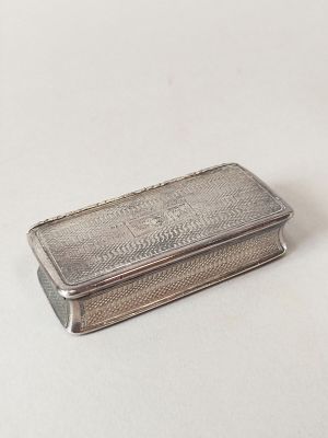 un étui à cigarettes ancien en argent posé sur une surface blanche